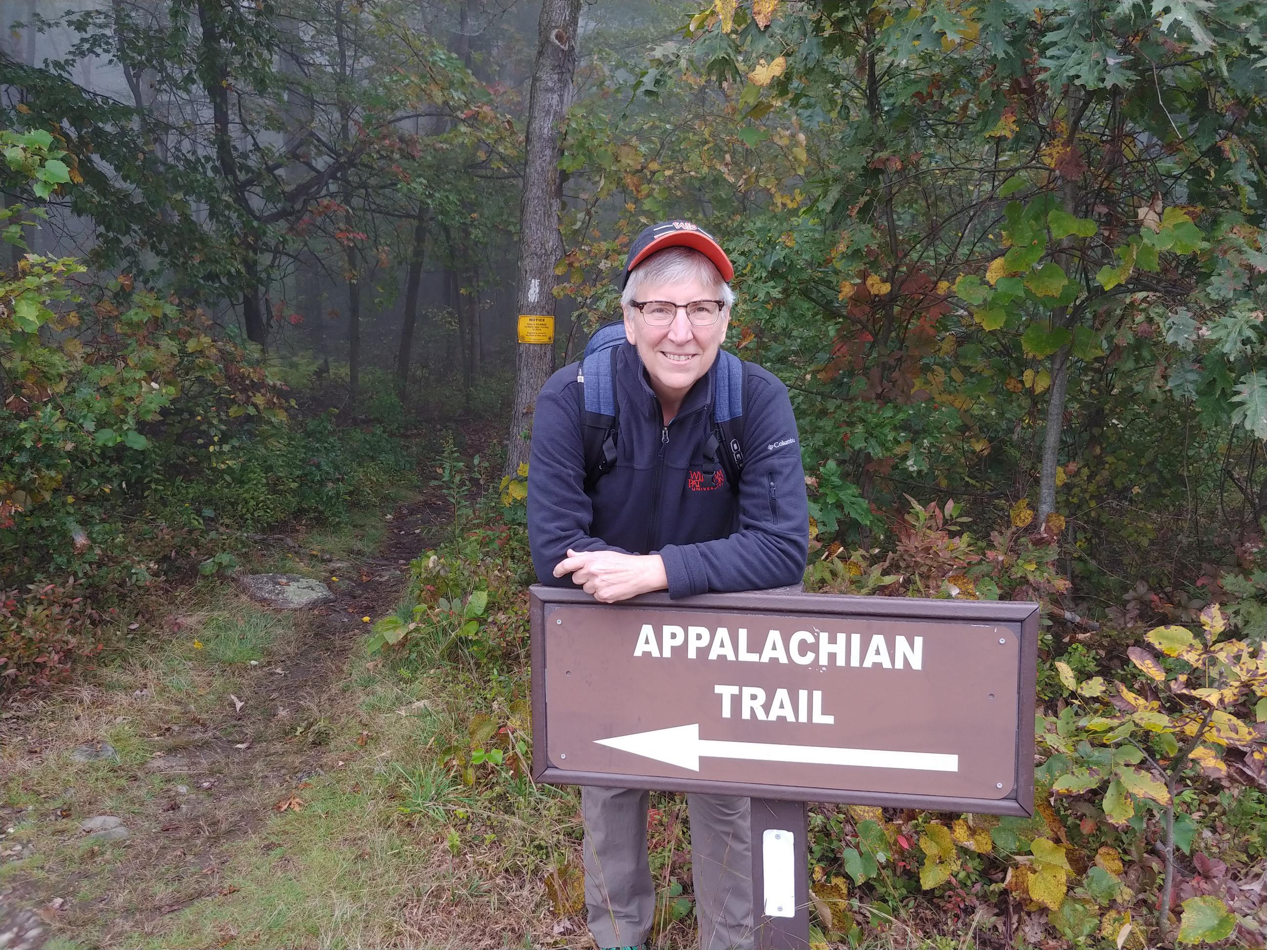 "Laura standing behind Appalachian Trail sign in the woods"