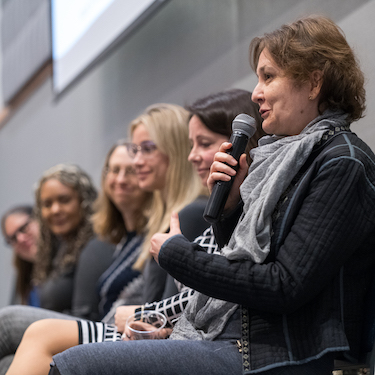Photo of Northeastern Professor of Mathematics Emma Turian, Ph.D., holding a microphone and speaking on a career panel during a Women in Science Conference.