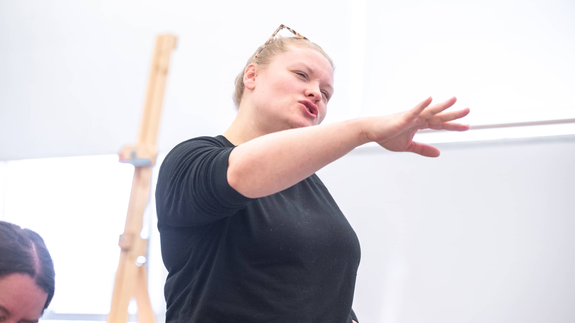 A female instructor uses her hands to mimic the motion of painting during an Art Education class at NEIU