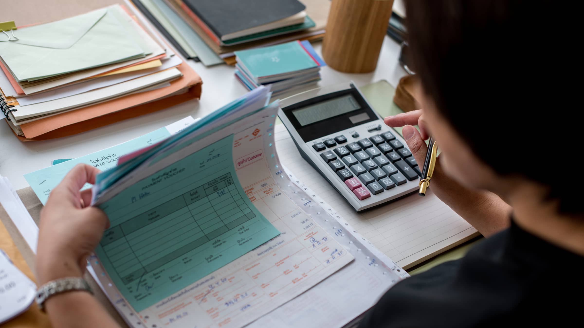 An adult accounting student at NEIU reviews tax forms while using a calculator