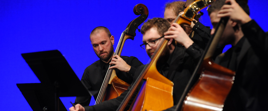 Four musicians perform on stringed instruments.