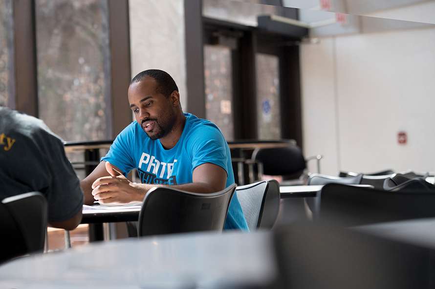 A student wearing a blue shirt sits at a table