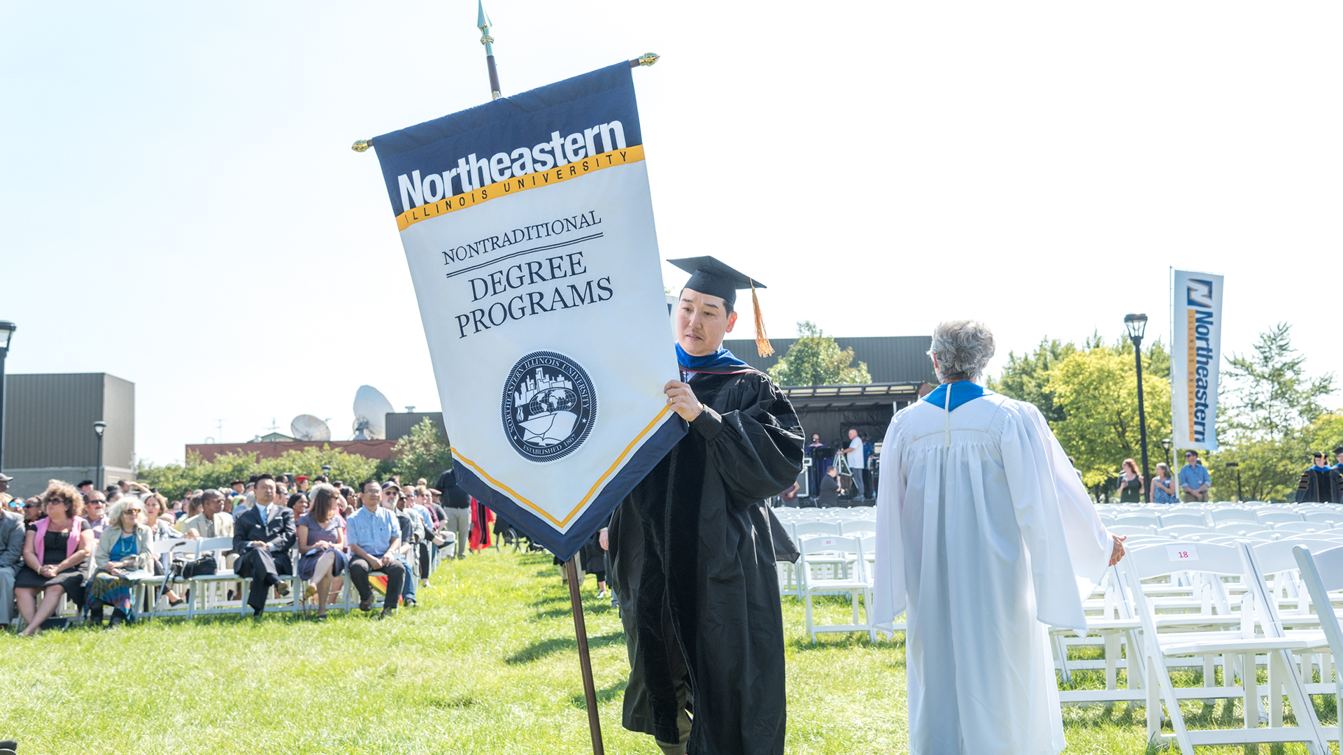 A graduate carrying a Nontraditional Degree Programs banner.