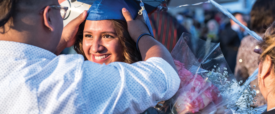 Student in graduation cap smiling at Commencement.