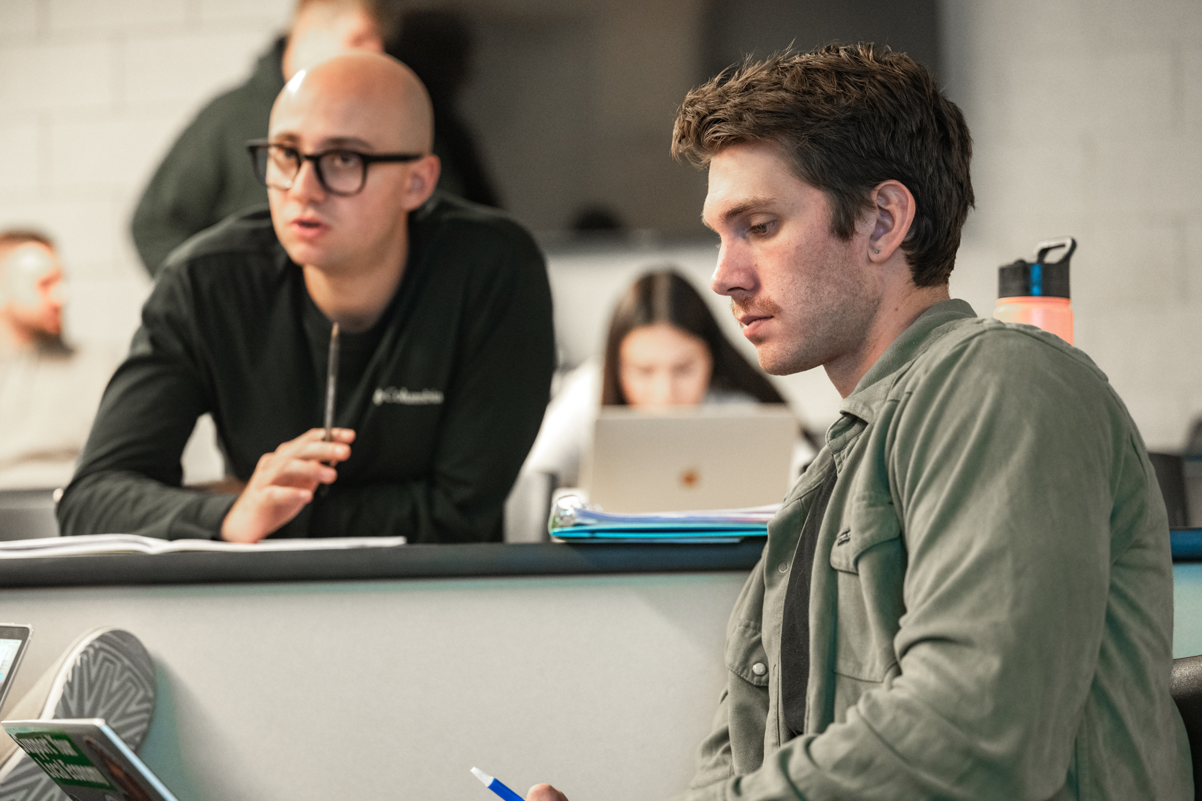 two students seated in a classroom, in the middle of a discussion