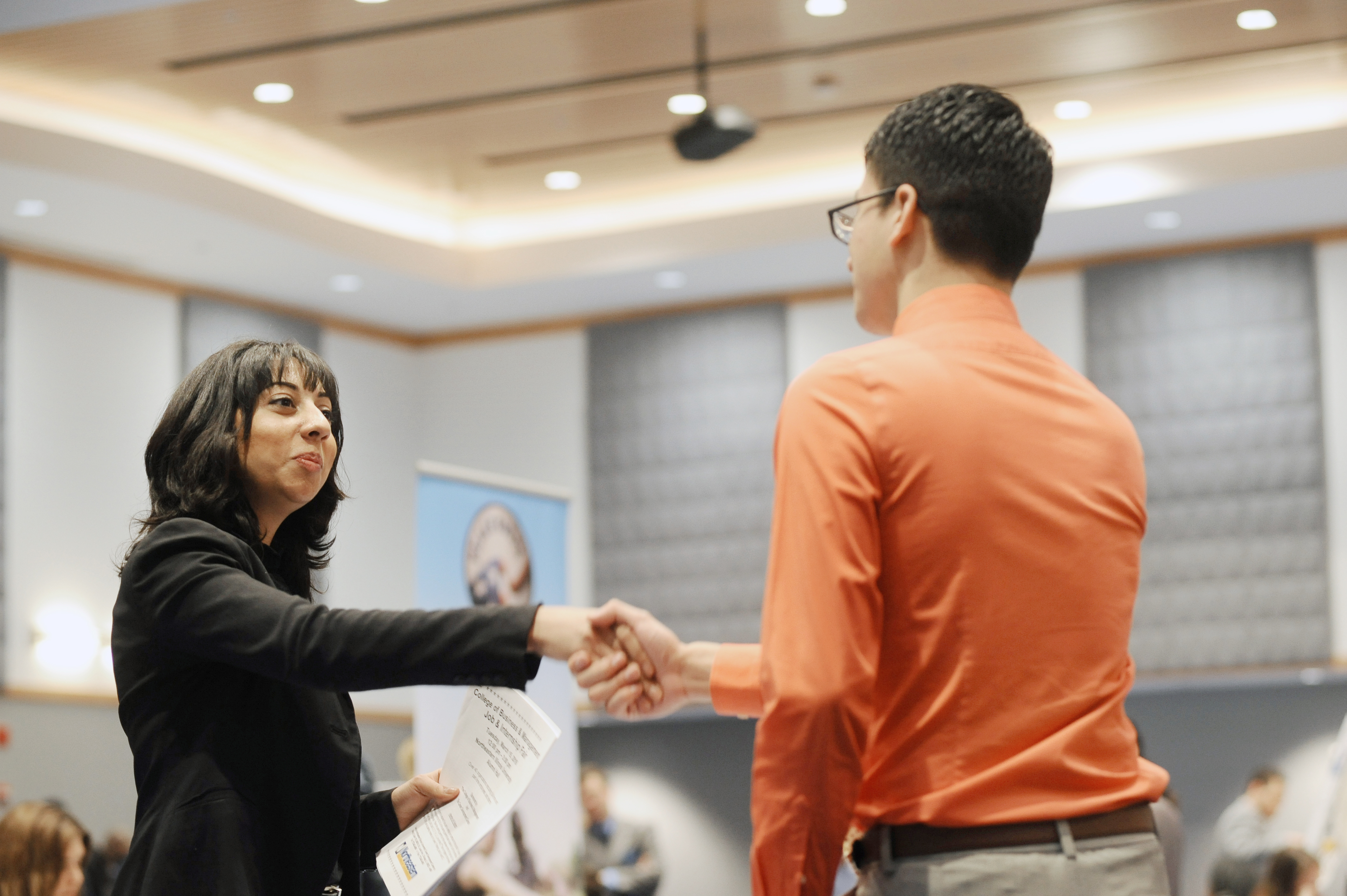A student is shaking hands with a man at a job fair 