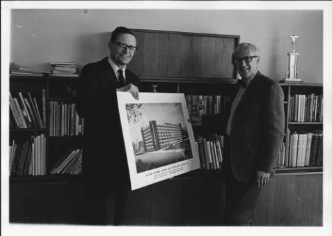 Jerome Sachs (right) and John Holm, project manager from Ralph H. Burke, Inc., hold a rendering of a proposed parking structure in the late 1960s.