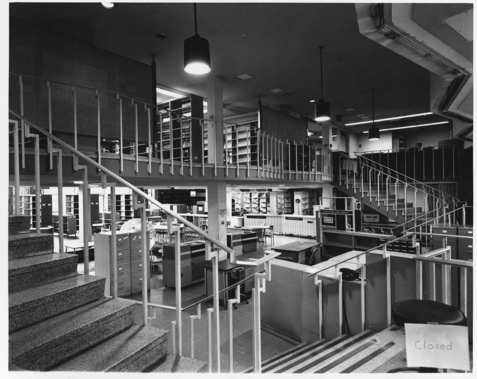The shelves of the old library are empty as the collection is relocated to the new library in 1976. In the mid-1970s, the University library occupied what is now the Office of Enrollment Management Services.