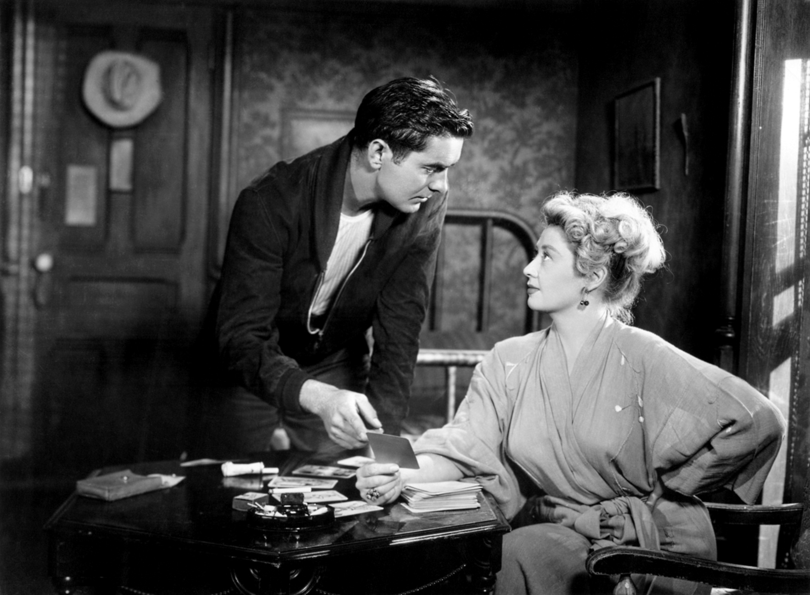 A still image from the film "Nightmare Alley" with a standing man and a seated woman