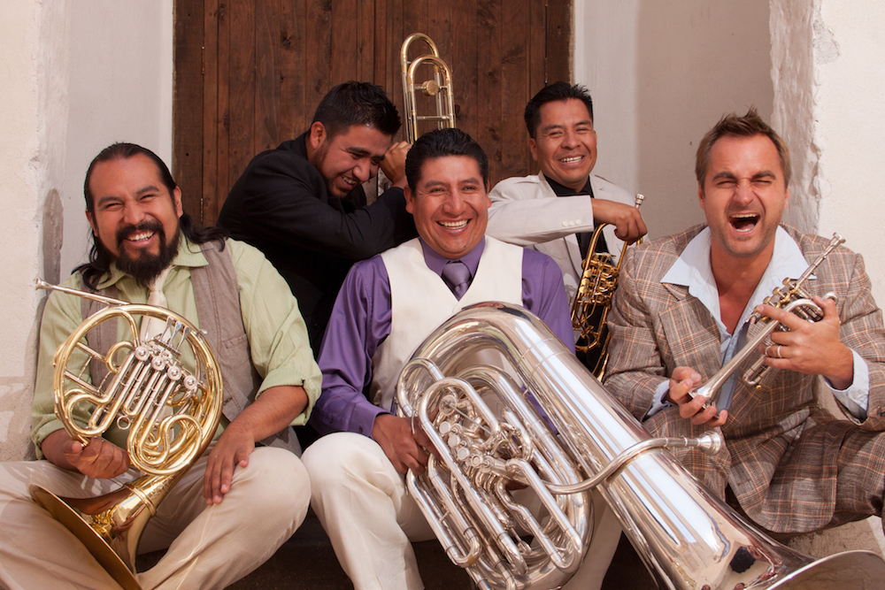 M5 Mexican Brass band members laughing and holding brass musical instruments