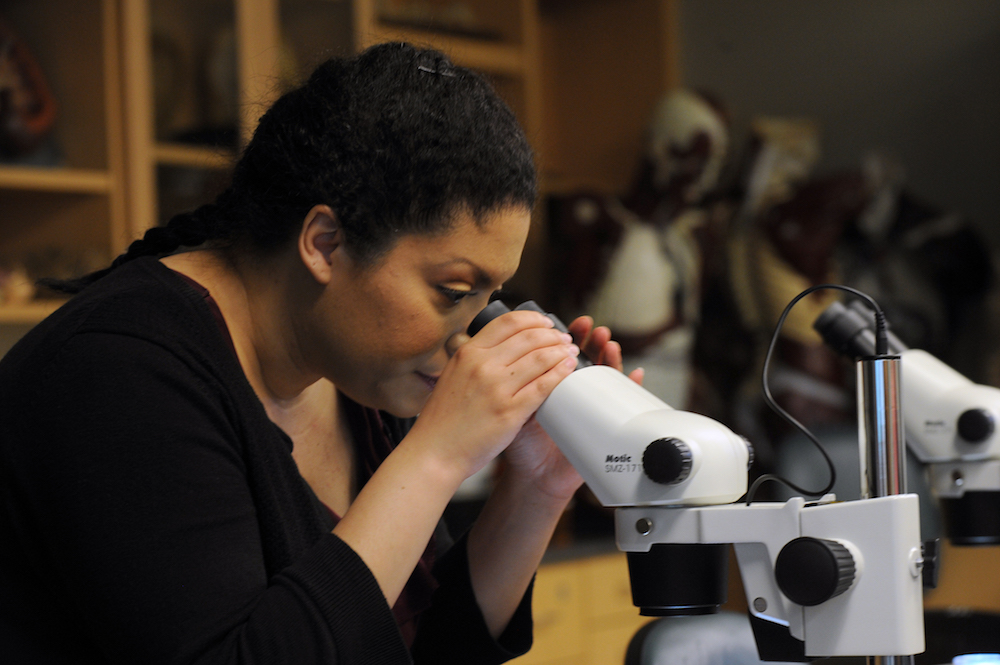 Economics graduate Rut Ortiz look uses a microscope in the lab
