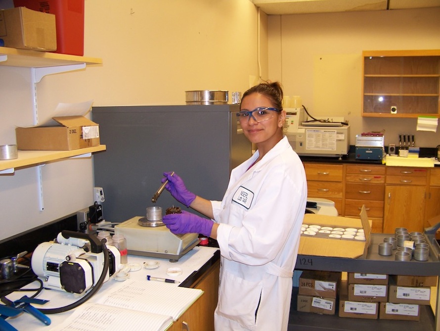Cindy Calderon studying rock samples in a lab.
