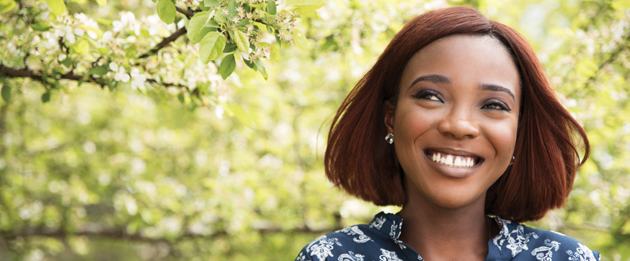 Margo Odiko-Pim smiles with tree leaves in the background.