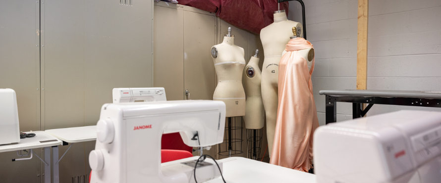 image of the costume shop with three mannequins in the background and two sewing machines in the foreground.