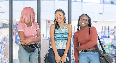 A group of three students smiling on main campus 