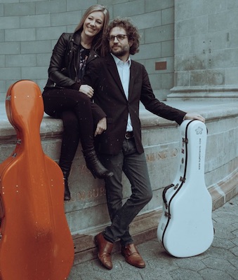 The two musician of Boyd Meets Girl stand against a wall with their instrument cases