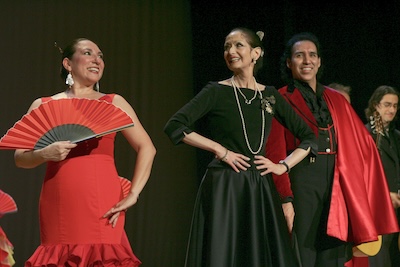 A photo of Irma Suárez Ruiz (left), Dame Libby Komiako (center) and Jorge Pérez smiling on a stage after an Ensemble Español dance performance. 