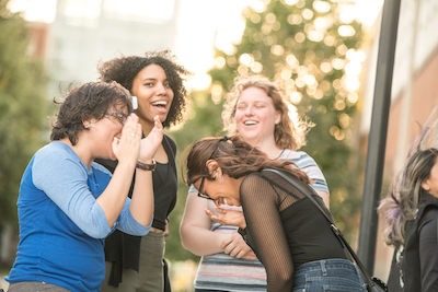 Four students smiling and laughing outdoors