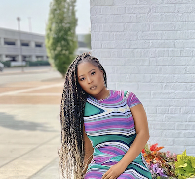 A photo of Gladie Ngiama wearing a blue, purple, green and white striped dress.