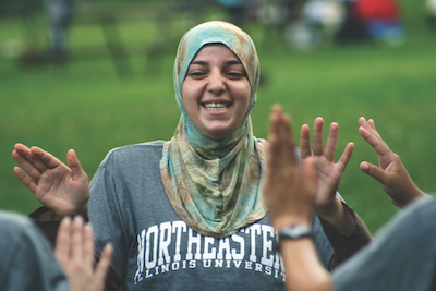 Photo of a student wearing an NEIU t-shirt getting high fives from peers