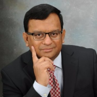 A photo of Jagannath Bobji wearing a dark colored suit against a gray background.