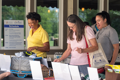 President Gibson and two others browse the silent auction items at the Kane Outing