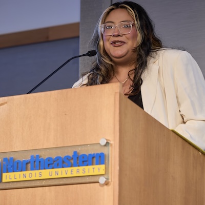 A photo of Cassaundra Garcia, speaking at a podium, accepting her Alumni Award.