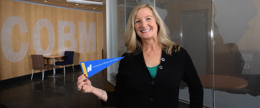 Julia Anderson smiles into the camera in front of a "COBM" sign.