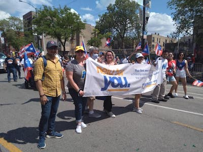 Puerto Rican People's Day participants hold a banner reading NEIU For You