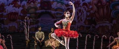A ballerina wearing a red tutu poses with one arm raised