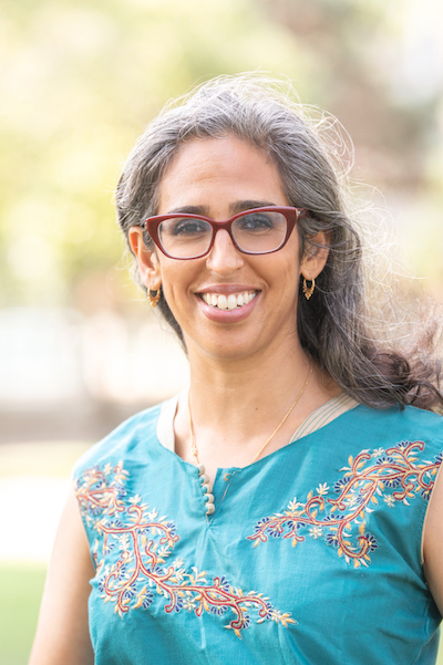 Dr. Shireen Roshanravan wearing glasses and a turquoise blouse with embroidery, smiling in a photo