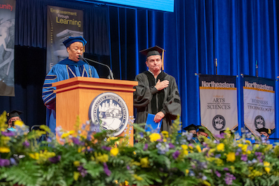 Juan Gabriel Moreno stands on stage next to Dr. Gibson