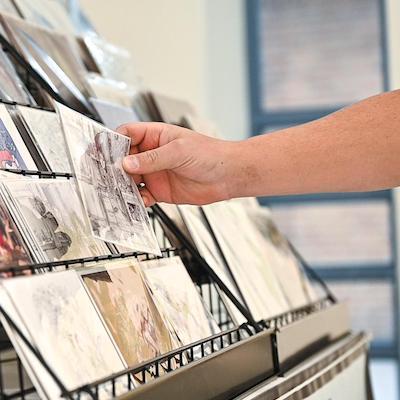 A hand selects a card from a display rack