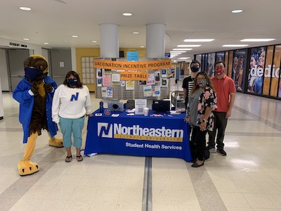 Photo of Goldie with Northeastern students and staff at the VIP prize pick up table in Village Square