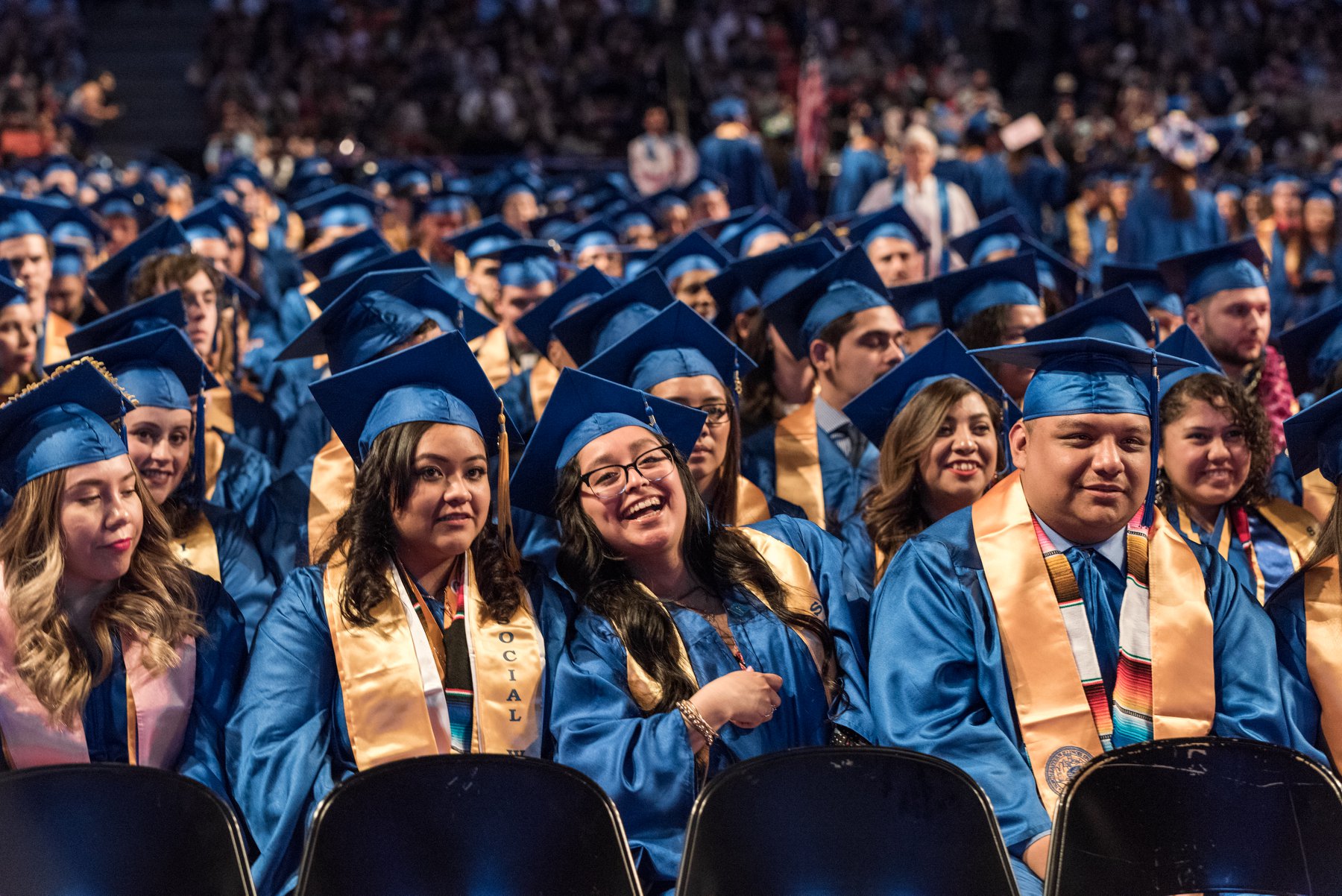 Graduates smile while wearing blue caps and gowns.