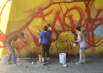 Photo of three people cleaning the mural near El Centro with cleaner and brushes
