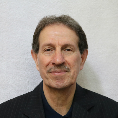 Photo of Alireza "Reza" Dorestani in a black suit against a gray back drop