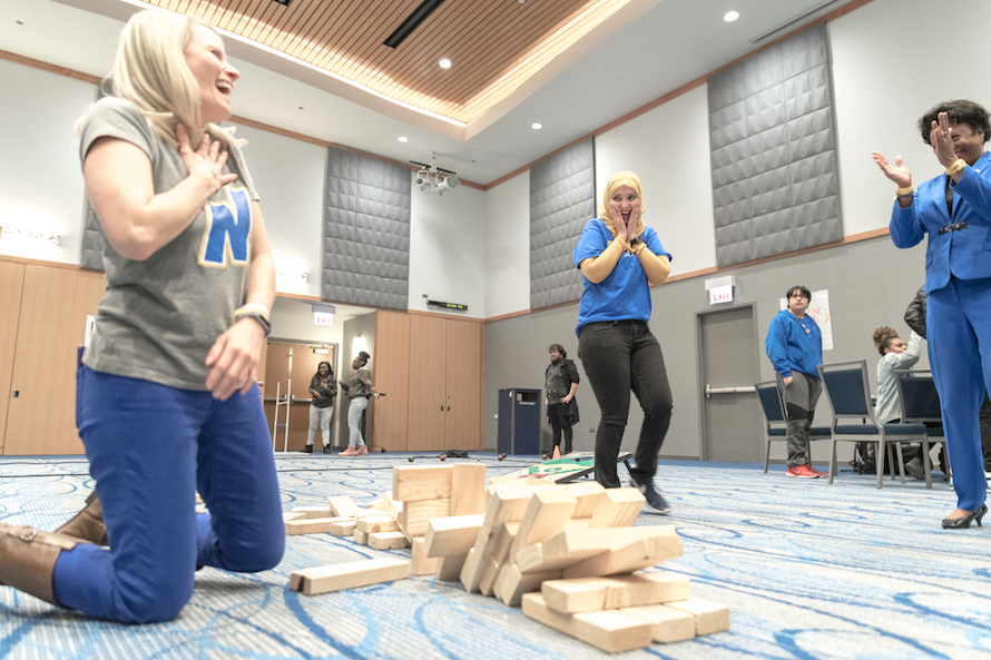 President Gibson watches carefully as an FYE Peer Mentor removes a block from giant jenga tower