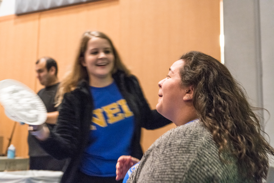 An FYE Peer Mentor nervously laughs with eyes closed as a student pies her in the face
