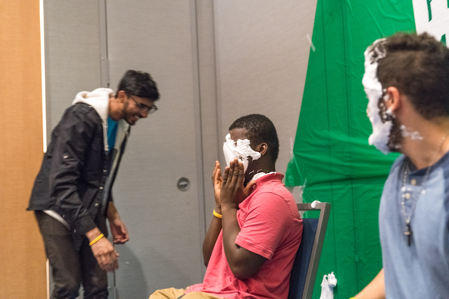 FYE Peer Mentors faces covered in shaving cream after getting pied as an onlooker laughs