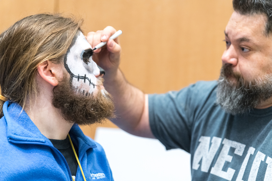 Advisor Jaime Mendoza paints a skull on an FYE Peer Mentor's face