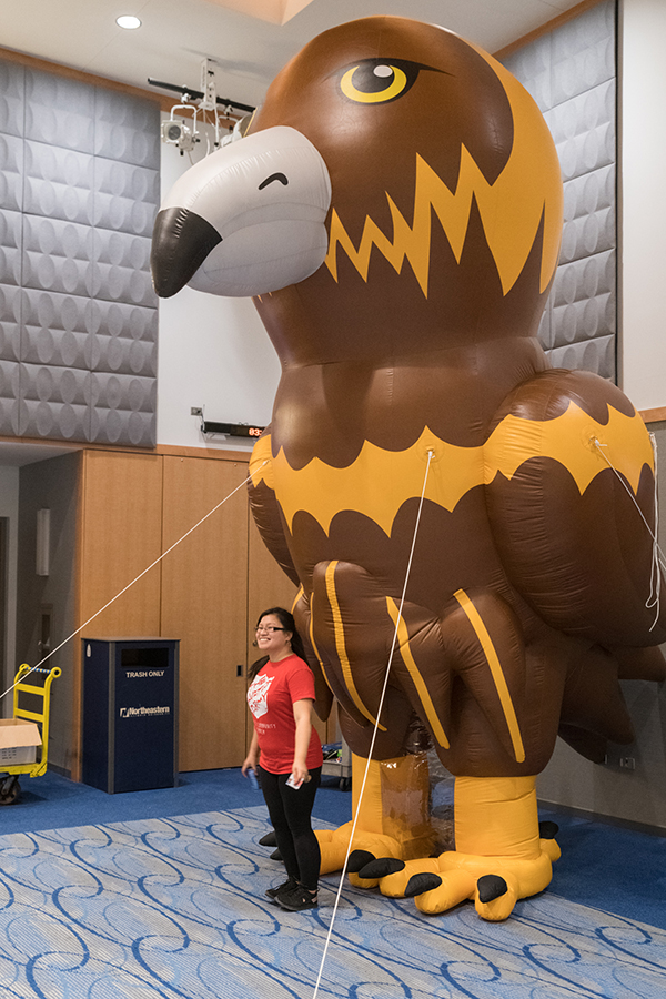 Giant inflatable Goldie mascot towers over a student.