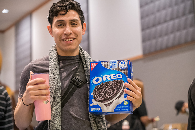 Student poses with a box of Oreo cookies.