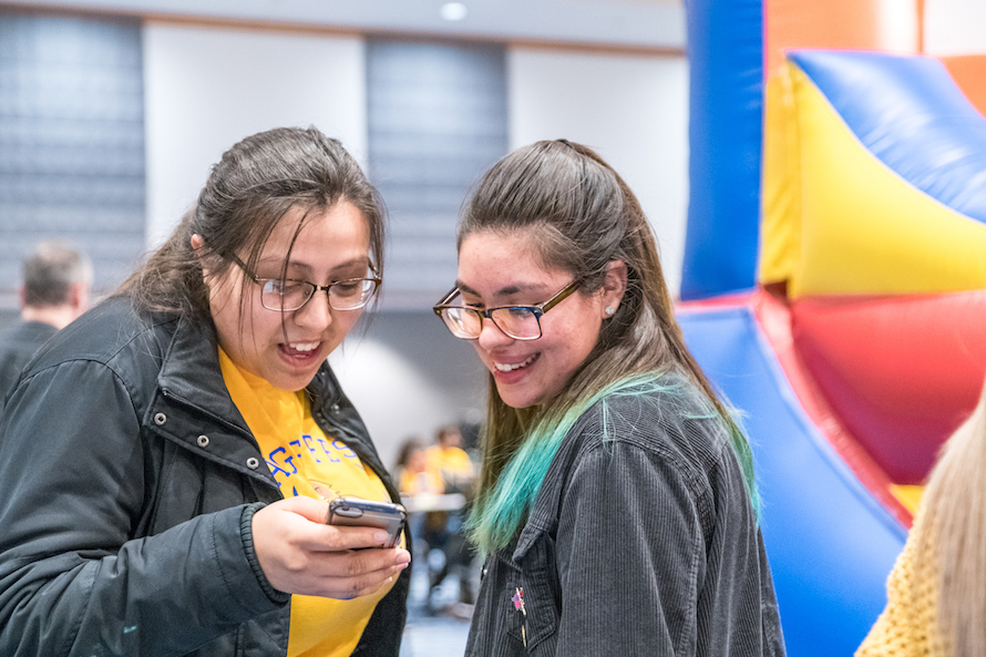 Two students smiling and connecting over a cellphone