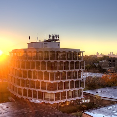 The sun rises behind the Sachs building