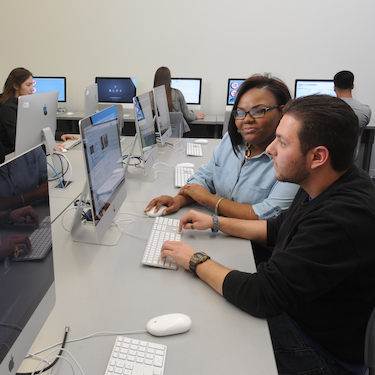 A photo of students sitting at computers in one of the labs at Northeastern's El Centro location.