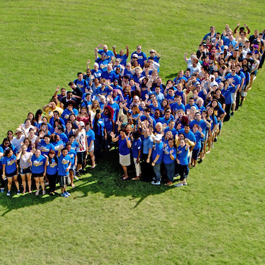 Photo of Northeastern's Flying N logo made up by a group of people wearing blue shirts. 