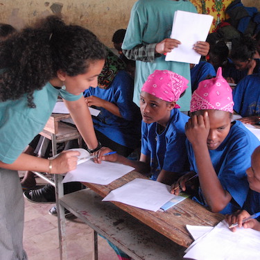 A photo of a Peace Corps volunteer with girls learning in a classroom in Africa. Photo courtesy of the Peace Corps.