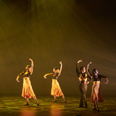 Ensemble Español performing "Sur." Dancers are wearing black and yellow costumes and are covered in yellow/green stage light. Photo by Dean Paul/Courtesy of Ensemble Español.