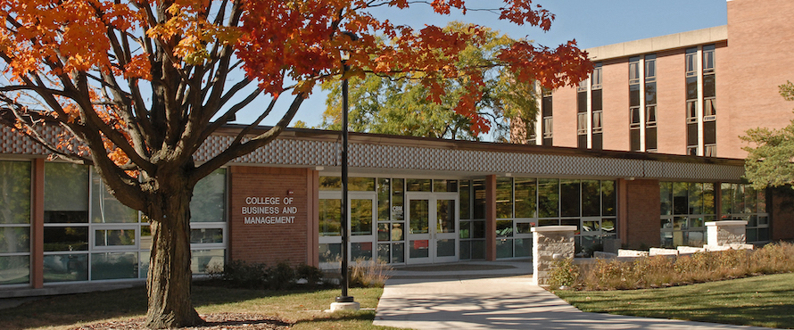 Photo of the exterior of the College of Business and Management with a tree with orange and red leaves